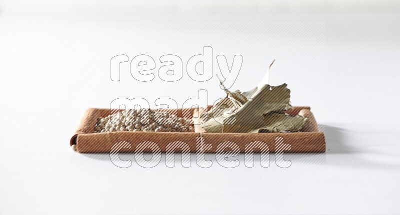 2 squares of cinnamon sticks full of white pepper and bay laurel leaves on white flooring
