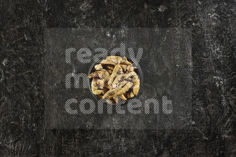 وعاء فخار أسود ممتلئ بأصابع كاملة من الكركم المجفف على خلفية سوداء