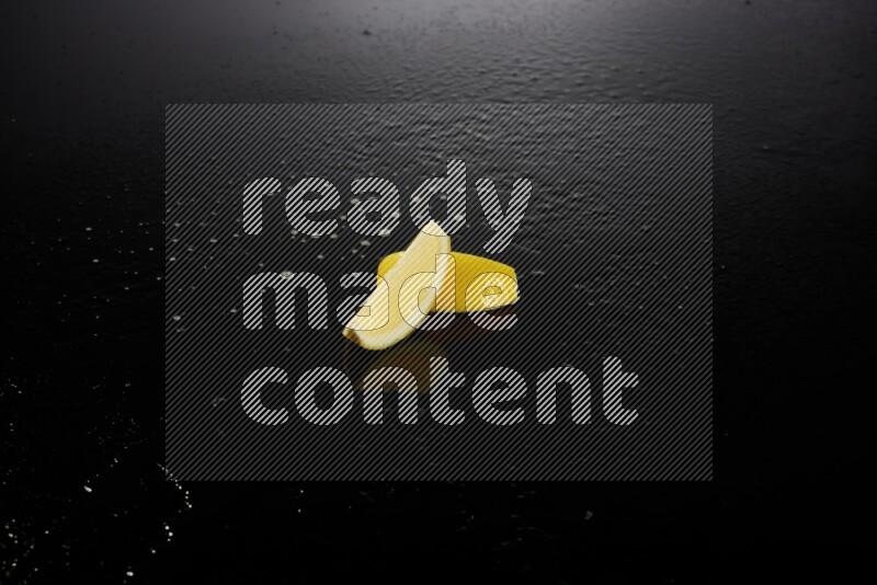 Lemon wedges with water drops, and droplets on black background