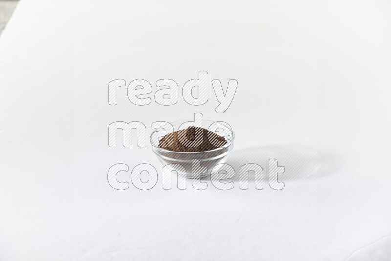 A glass bowl full of cloves powder on white flooring