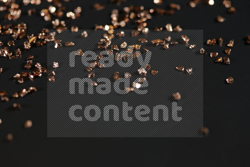 قطع زجاجية برونزية لامعة متناثرة على خلفية سوداء