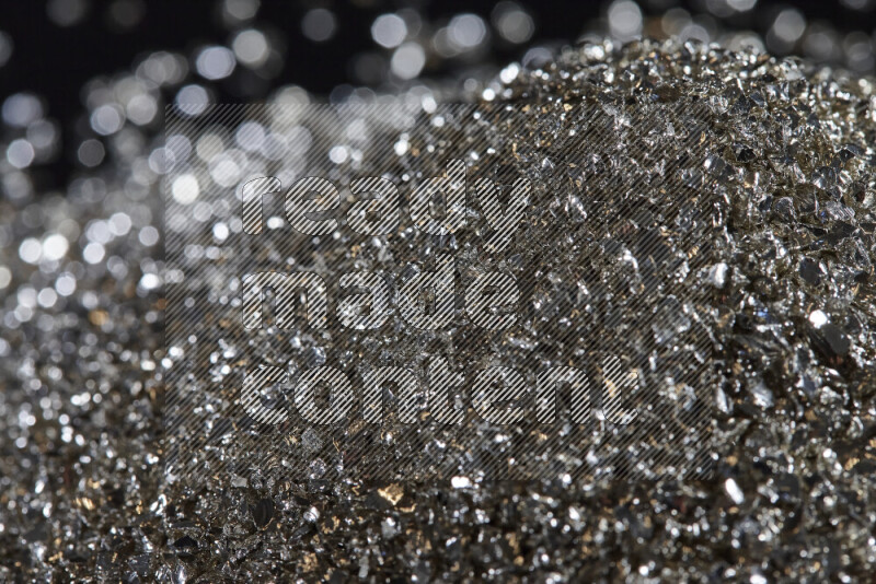 Silver shimmering fragments of glass scattered on a black background