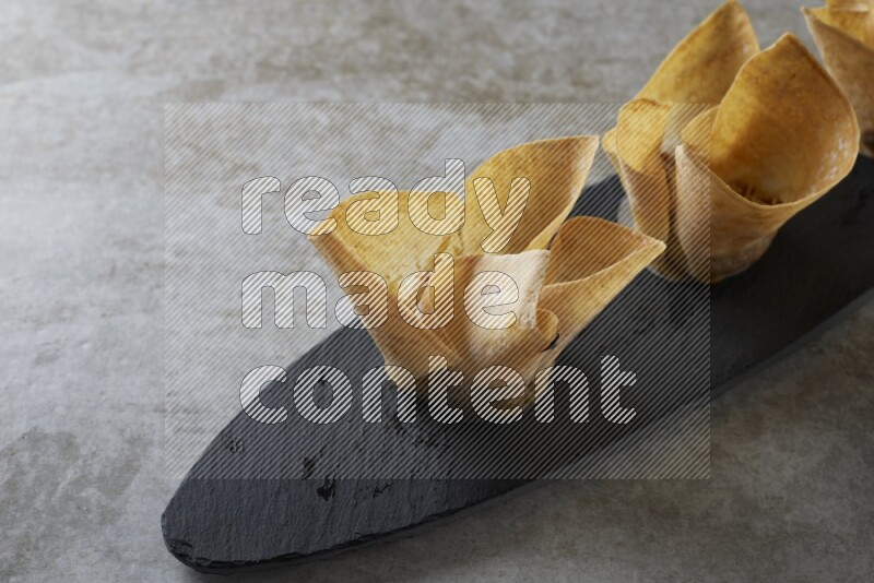wonton cups with soy sauce ramkin on oval slate on grey textured counter top