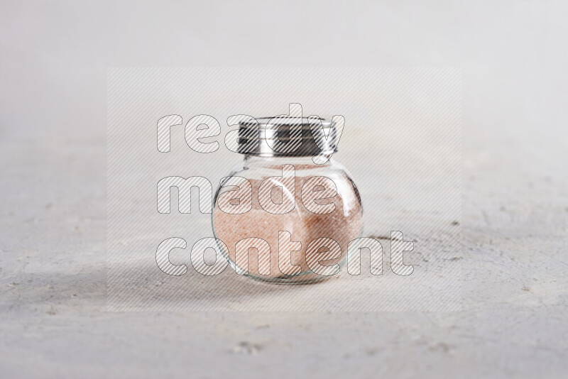 A glass jar full of fine himalayan salt on white background