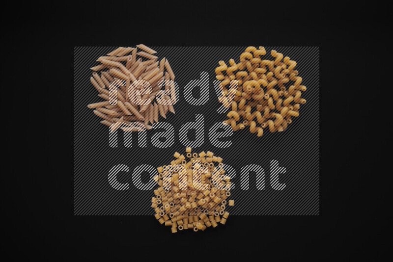 Different pasta types in bunches on black background