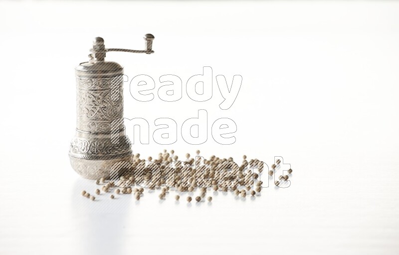 White pepper beads with a metal grinder on white flooring