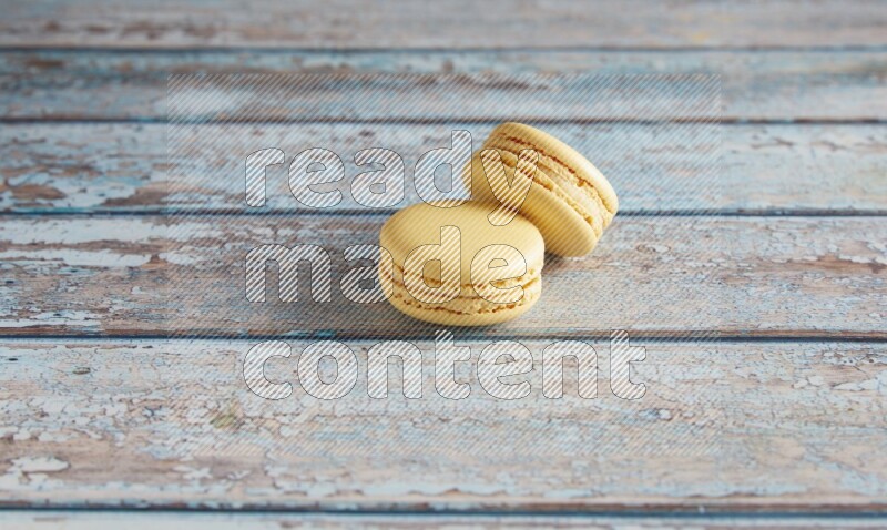 45º Shot of two Yellow Vanilla macarons on a light blue wooden background