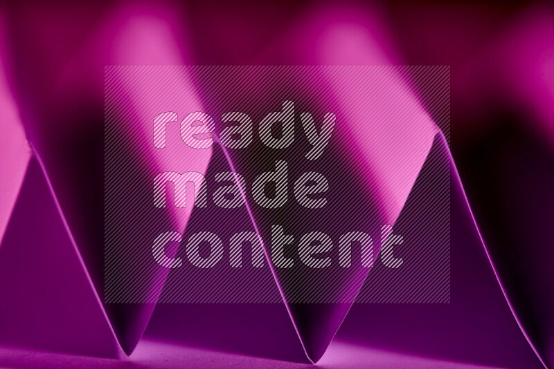 A close-up abstract image showing sharp geometric paper folds in purple gradients