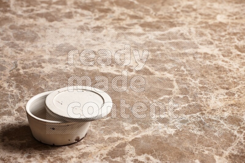 A white pottery bowl on beige marble background