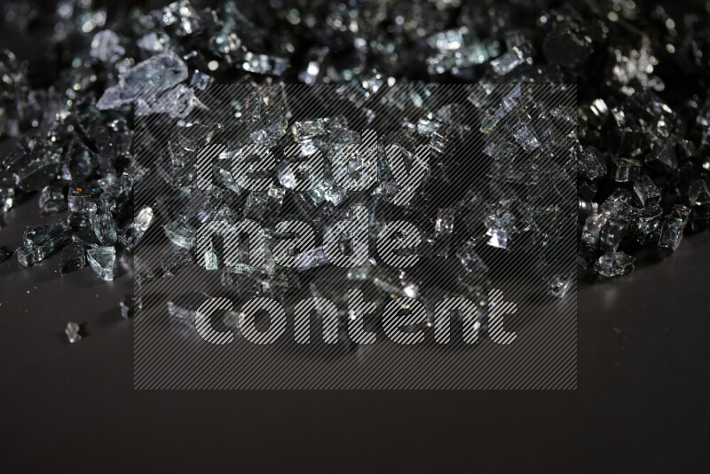 Transparent black fragments of glass scattered on a black background