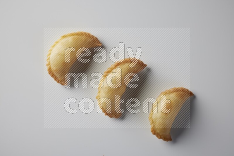 Three fried sambosa from a top angle on a white background