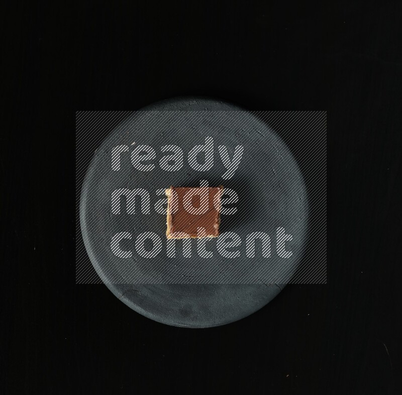 Assorted desserts in a black pottery plate on black background