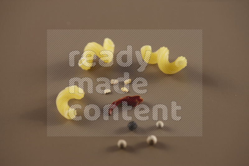 معكرونة مع مكونات متنوعة من الطماطم والثوم والبصل والفلفل الأحمر والفلفل الأسود والفلفل الأبيض وأوراق الغار وإكليل الجبل والهيل على خلفية بيج