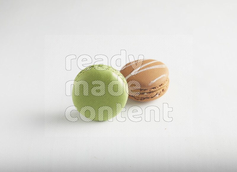 45º Shot of of two assorted Brown Irish Cream, and Green Pistachio macarons on white background