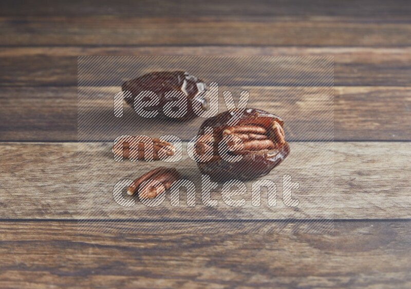 two pecan stuffed madjoul date on a wooden background