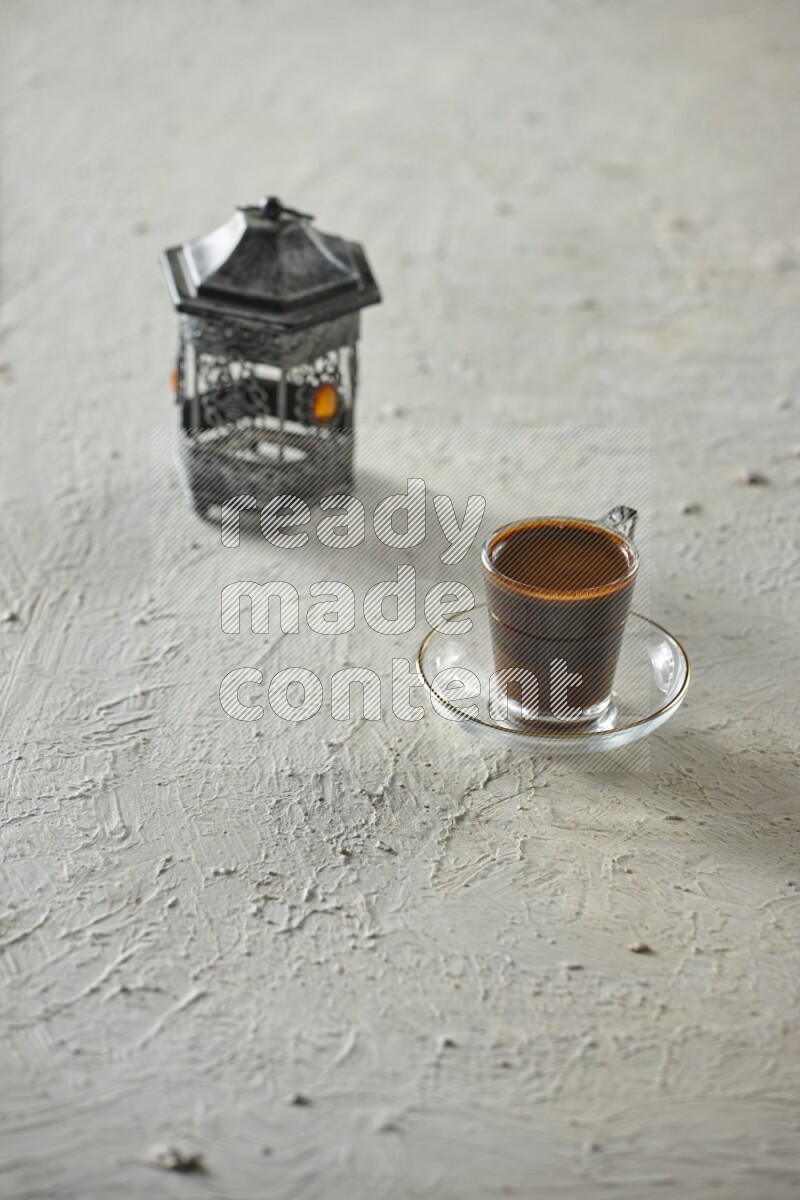 A silver lantern with different drinks, dates, nuts, prayer beads and quran on textured white background
