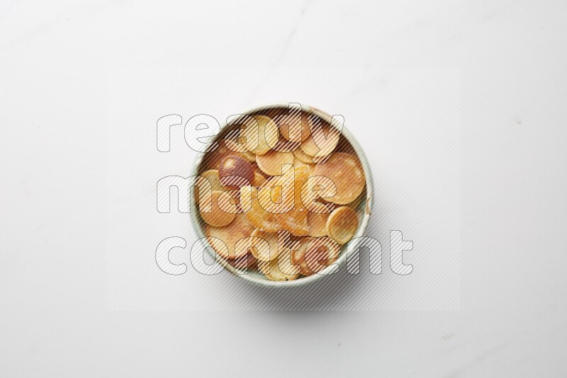 Top-view shot of orange candy cereal pancakes in a round bowl on white background