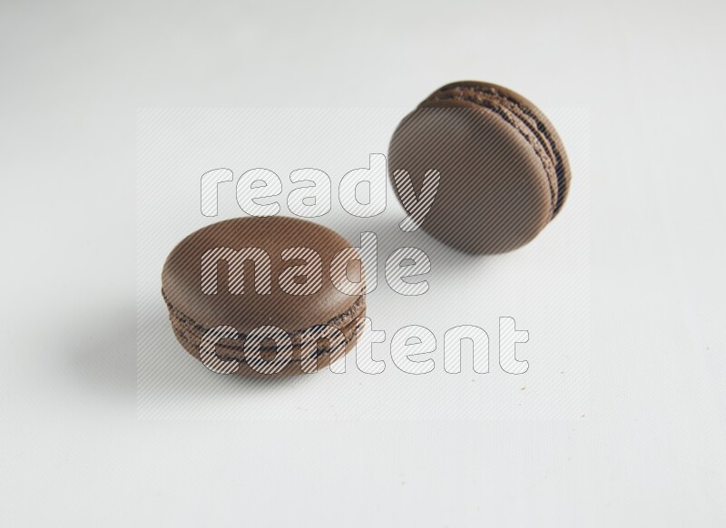 45º Shot of two Brown Dark Chocolate macarons on white background