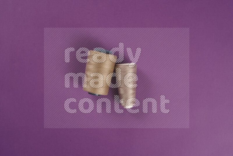 A beige collection of sewing and tailoring tools arranged on a purple background