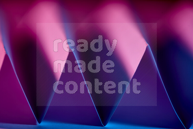 صورة مجردة مقربة تظهر طيات ورقية هندسية حادة بتدرجات اللون الارجواني