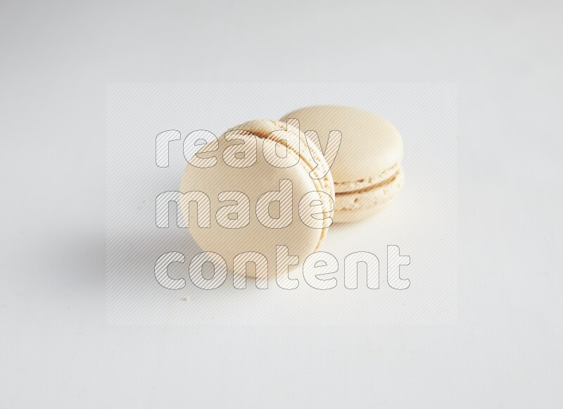 45º Shot of two White Caramel fleur de sel macarons on white background