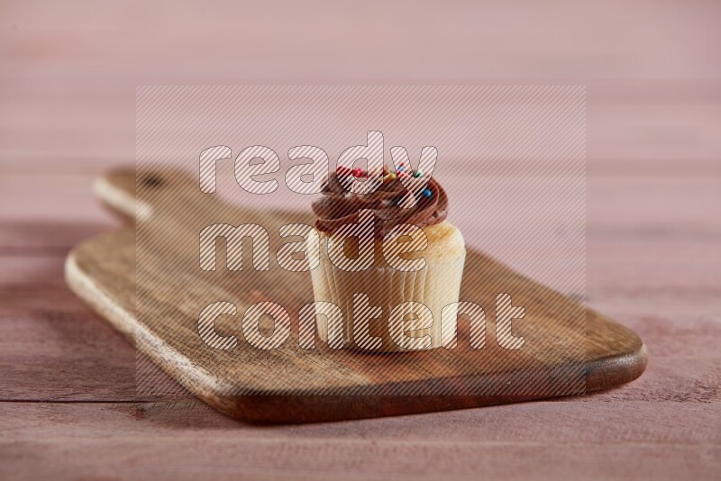 Vanilla mini cupcake topped with chocolate cream on a wooden board