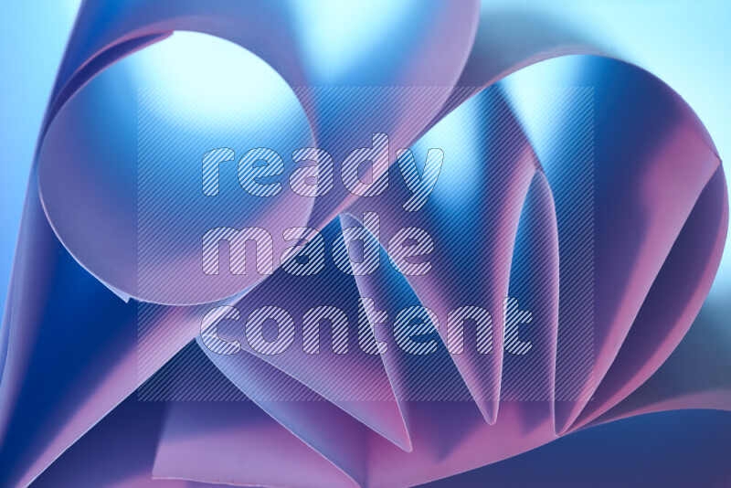 عرض فني لطيات الورق تخلق مزيج من الأشكال الهندسية، مضاءة بإضاءة ناعمة بدرجات اللون الأزرق والوردي