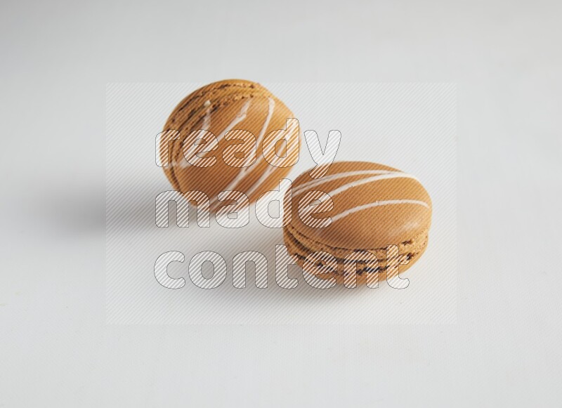 45º Shot of two Brown Irish Cream macarons on white background