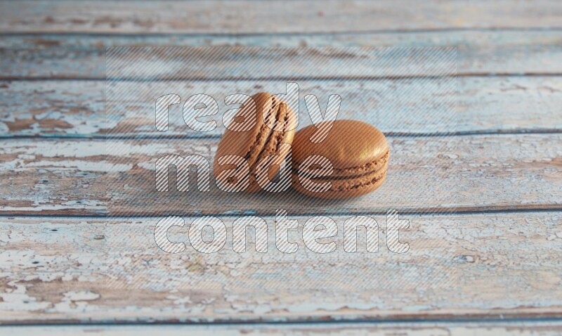 45º Shot of two Brown Coffee macarons on light blue wooden background