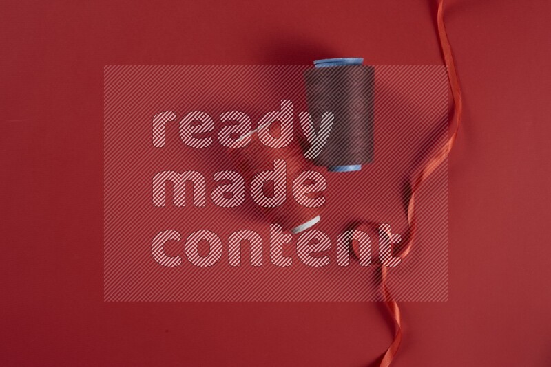 مجموعة من أدوات الخياطة والتفصيل حمراء اللون على خلفية حمراء