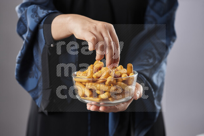 Woman in abaya holding different kinds of snacks in different positions