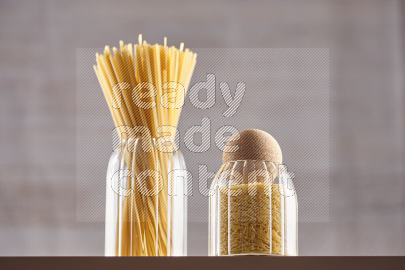 Raw pasta in glass jars on beige background