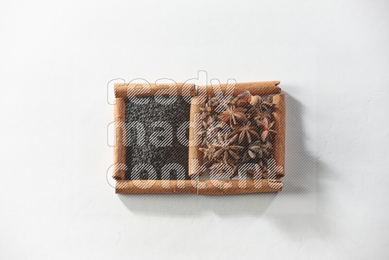 مربعان من أعواد القرفة ممتلئان بحبة البركة السوداء واليانسون النجمي علي خلفية بيضاء