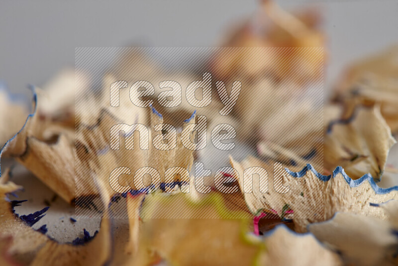 صورة مقربة تظهر كومة صغيرة من نشارة الأقلام ذات حواف ملونة متنوعة علي خلفية رمادية