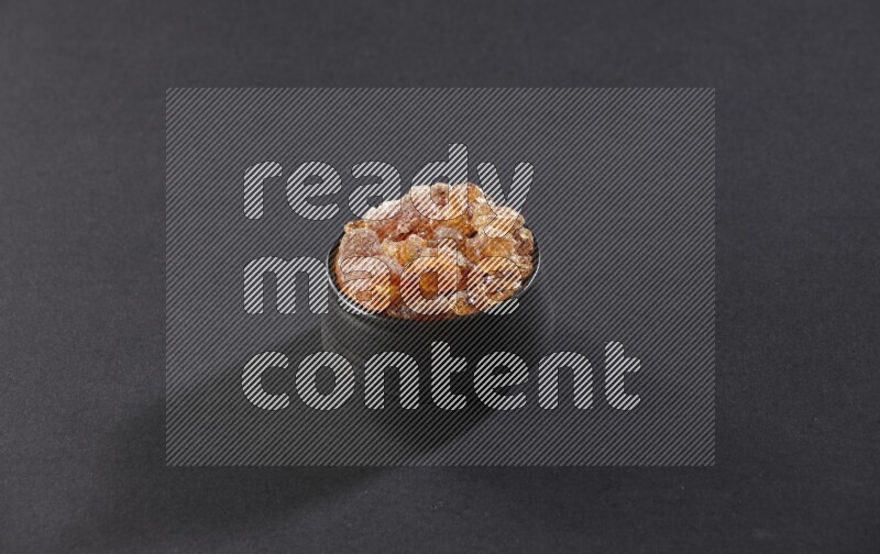 وعاء فخاري أسود ممتلئ بقطع الصمغ العربي علي خلفية سوداء