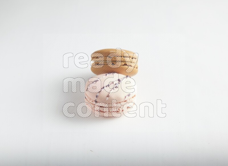 45º Shot of of two assorted Brown Irish Cream, and pink orange blossom macarons on white background