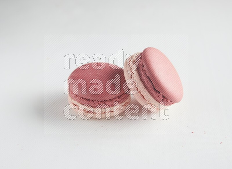 45º Shot of two Pink Litchi Raspberry macarons on white background