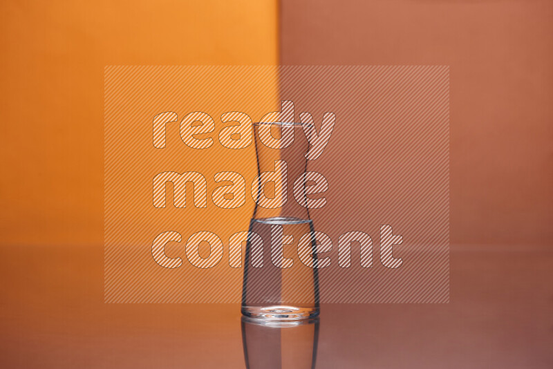 The image features a clear glassware filled with water, set against orange and dark orange background