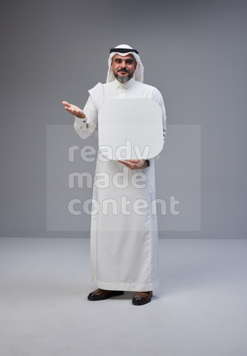 Saudi man Wearing Thob and white Shomag standing holding social media sign on Gray background