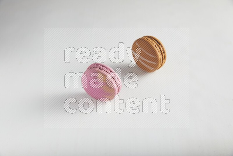 45º Shot of of two assorted Brown Irish Cream, and Purple Strawberry macarons on white background