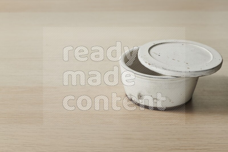 A white pottery bowl on light wooden background