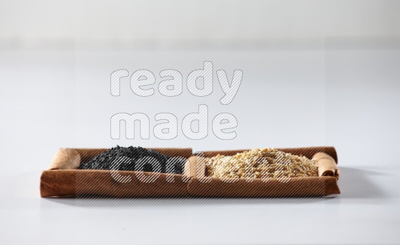 2 squares of cinnamon sticks full of sesame and black seeds on white flooring
