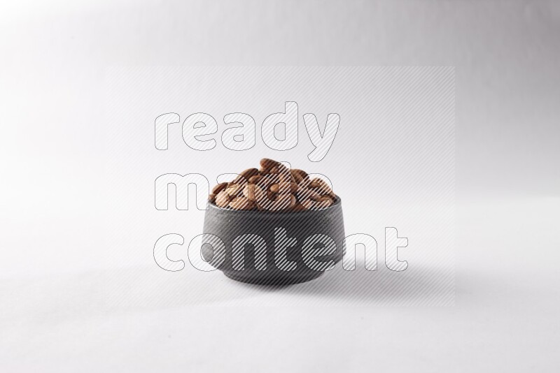 Almonds in a black pottery bowl on white background