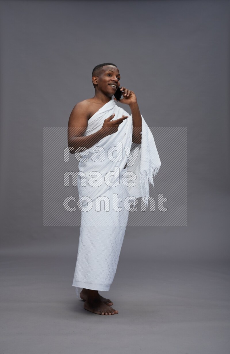 A man wearing Ehram Standing talking on phone on gray background