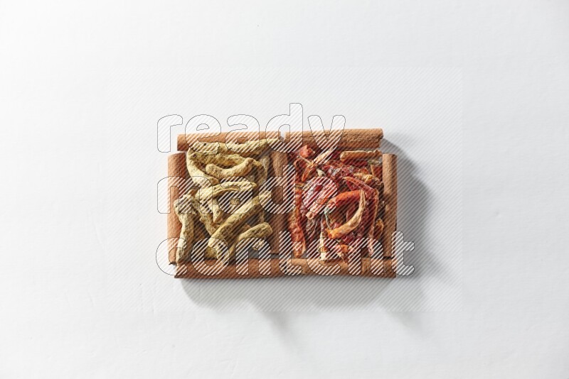 مربعان من أعواد القرفة ممتلئان بالفلفل الحار المجفف وأصابع الكركم علي خلفية بيضاء