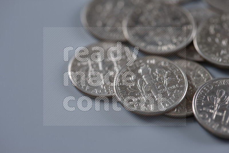 A close-up of scattered United States one dime coins on grey background