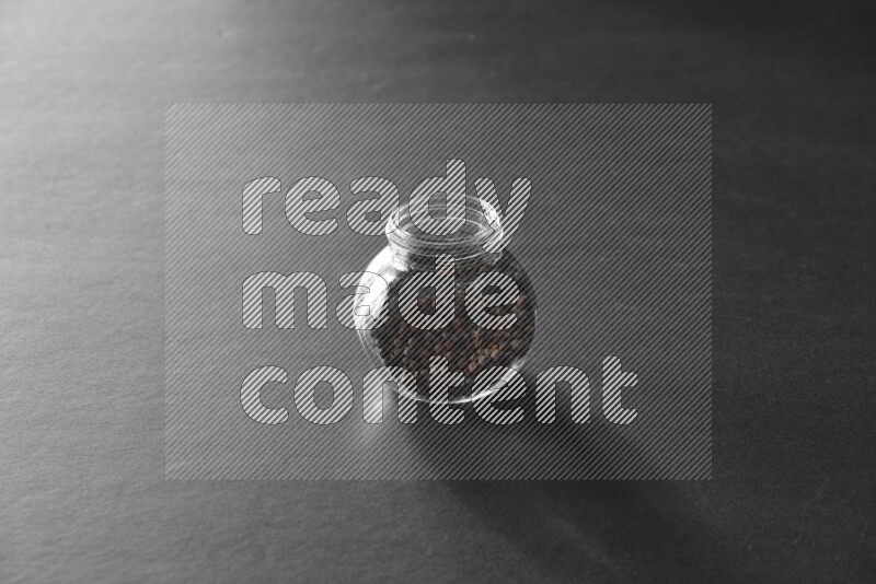 فلفل أسود في وعاء زجاجي علي خلفية سوداء