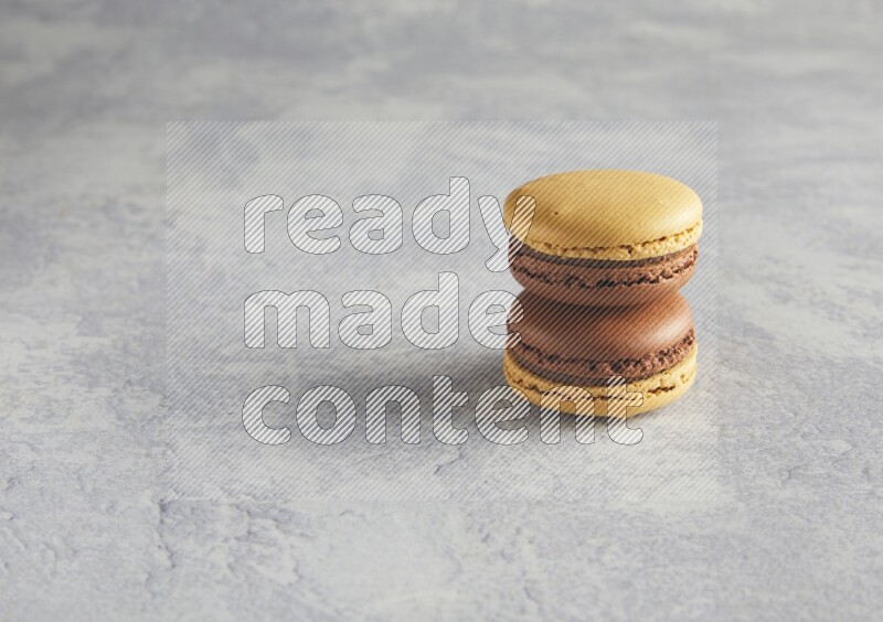 45º Shot of two Yellow and Brown Chai Latte macarons r on white  marble background
