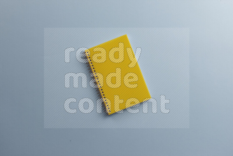A yellow notebook with different school supplies on blue background