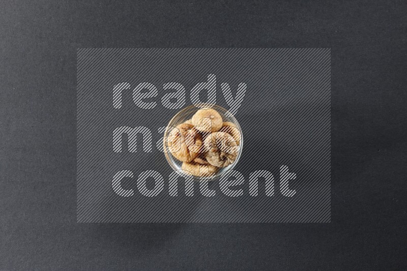 A glass bowl full of dried figs on a black background in different angles